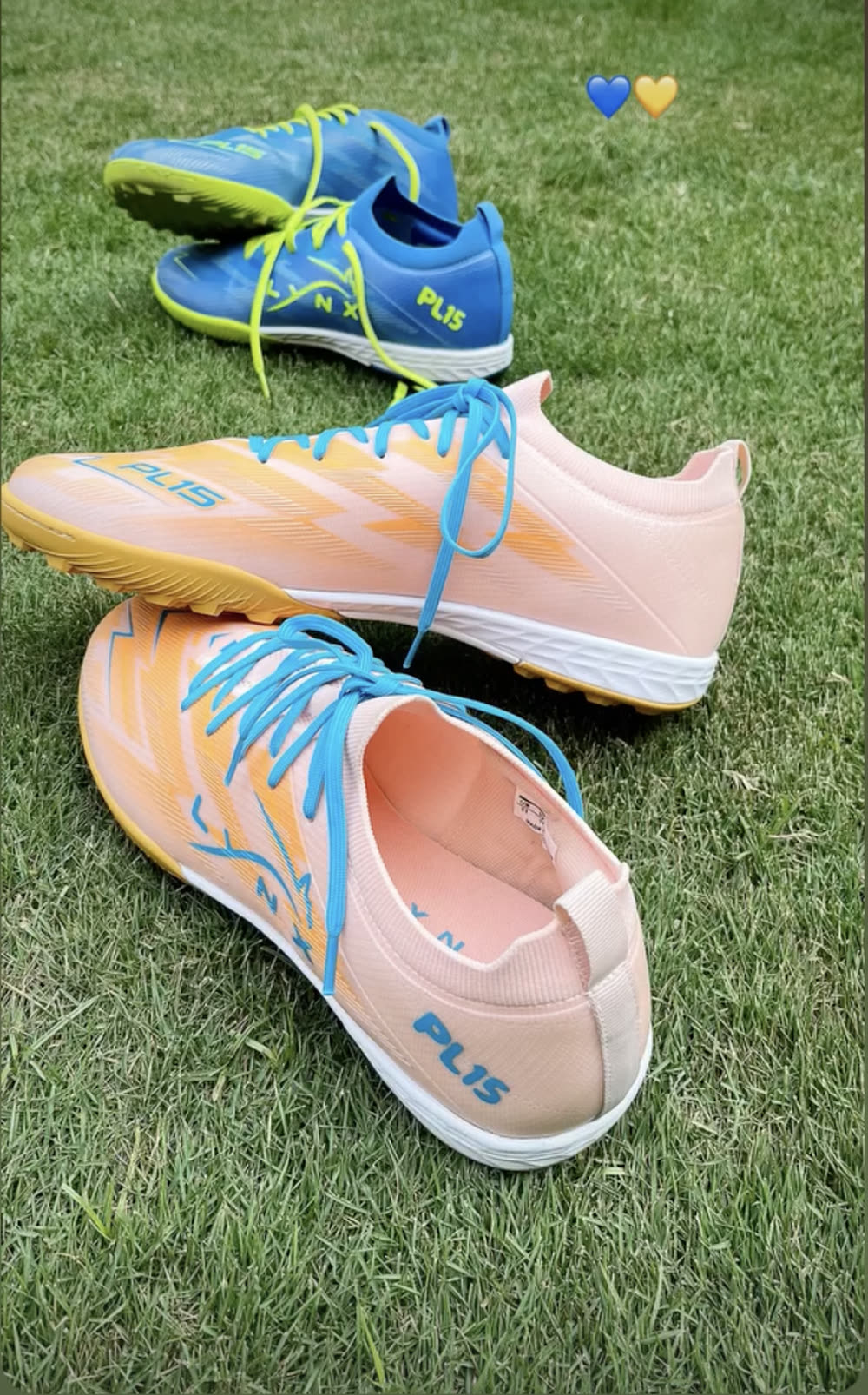 Two pairs of LYNX PL15 turf boots on grass, blue and peach