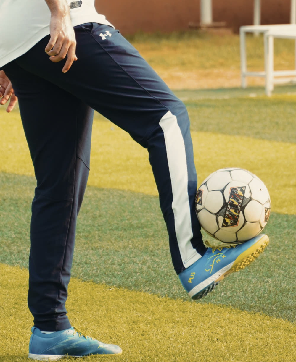 Player resting a football on a teal LYNX PL15 turf boot